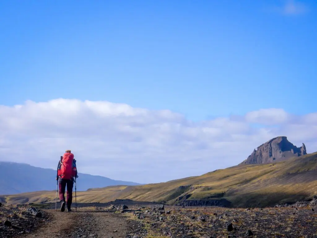 randonneur avec un sac à dos rouge sur un sentier dans un paysage islandais