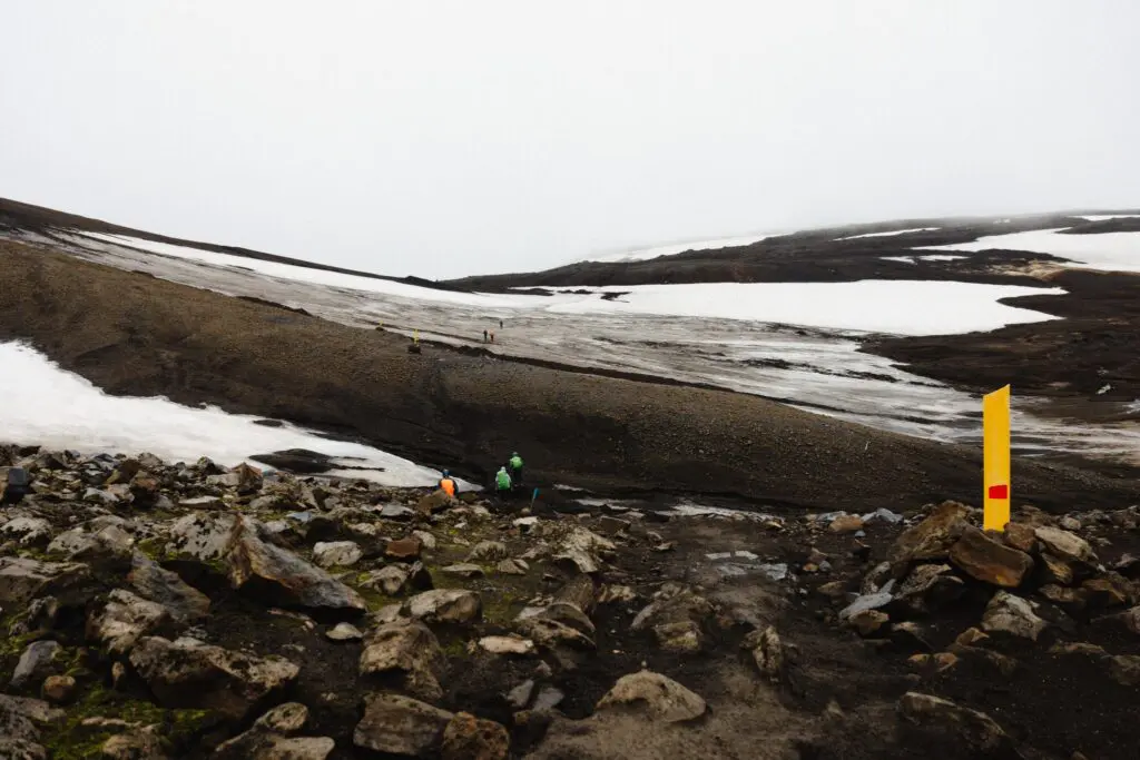 randonneurs sur un sentier enneigé et rocailleux en Islande