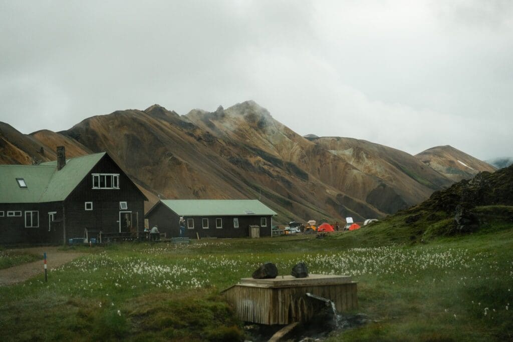mountain huts and tents in a valley with geothermal spring