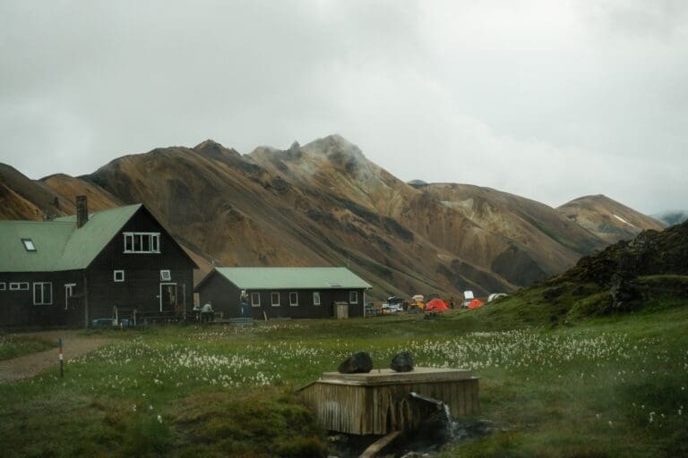 mountain huts and tents in a valley with geothermal spring